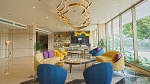 A modern lobby with a central seating area, a reception desk, and large windows offering a view of the outdoors. - Vivanta Kochi Aluva (Aluva)