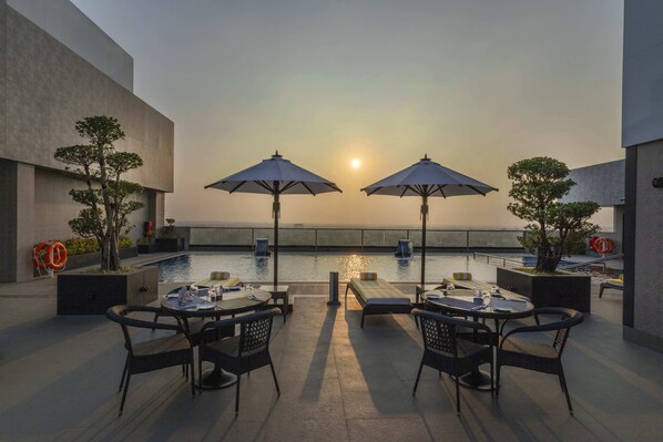 Eine Dachterrasse mit Pool, Sitzgelegenheiten und Sonnenschirmen.