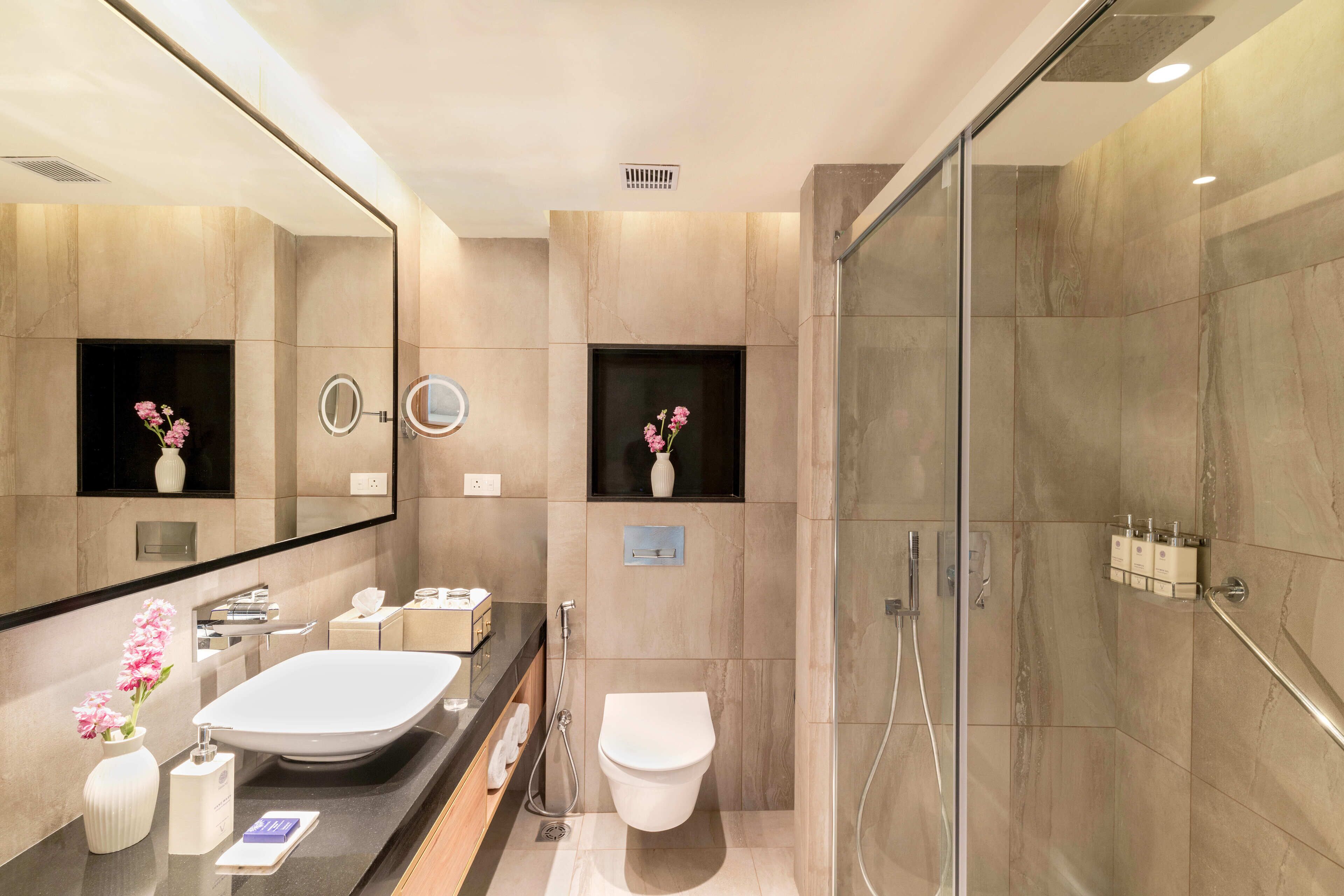 Un baño moderno con un espejo grande, un lavabo, un inodoro y una zona de ducha.