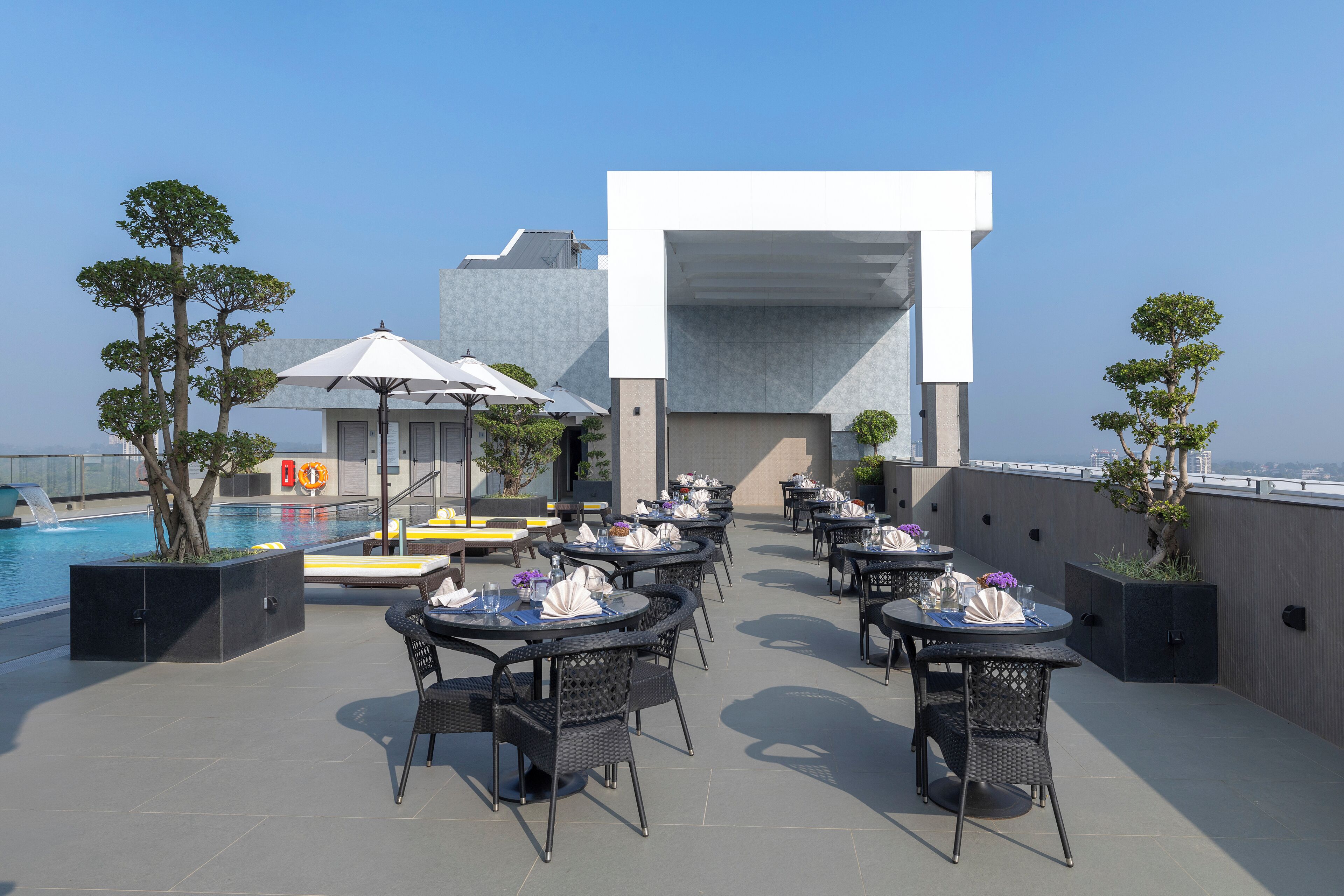 A rooftop terrace with outdoor seating, a pool, and a modern building structure.