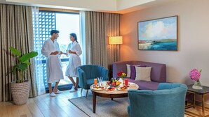 A hotel room with a dining area, a sofa, a coffee table with food, a plant, and a painting on the wall. - Vivanta Kochi Aluva (Aluva)
