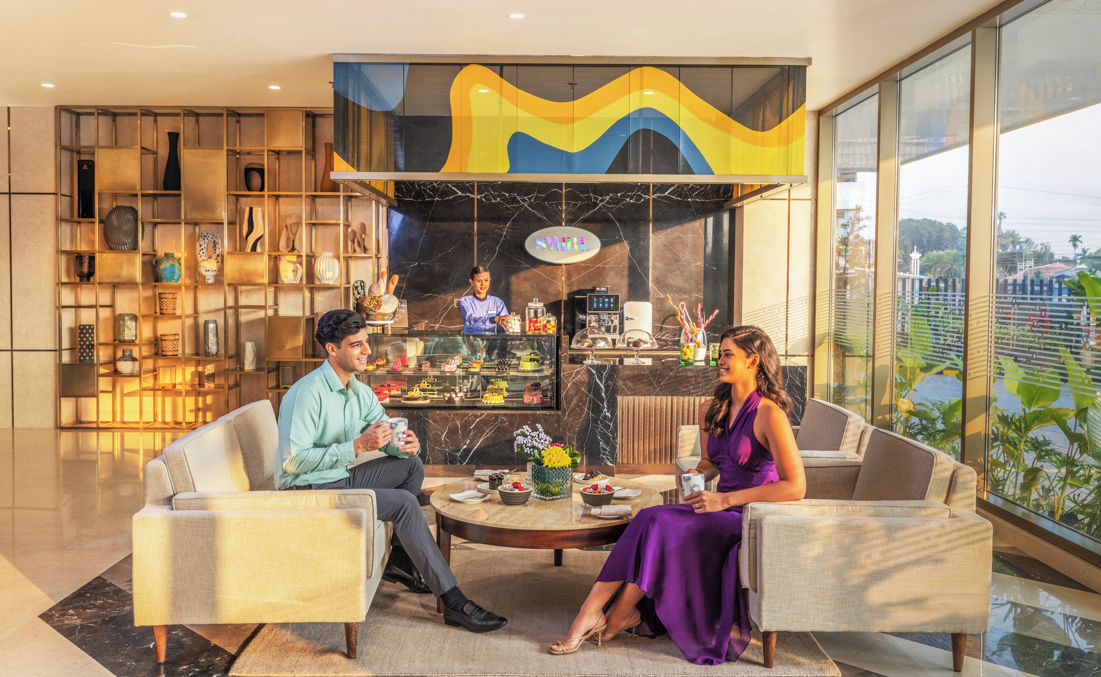 A modern interior with two sofas, a coffee station, and a view of the city.