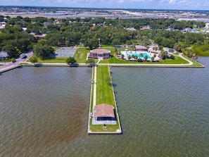 An aerial view of a waterfront property with a long, narrow building, a swimming pool, and a tennis court. - Pool, Waterfront Community, Palmetto Beach Compound #2 (Tampa)