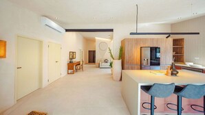 Una cocina moderna con armarios de madera, una isla central con taburetes de bar y un comedor con sofá y mesa de centro.