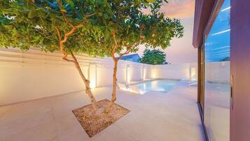 A modern indoor pool area with a tree and a glass wall.