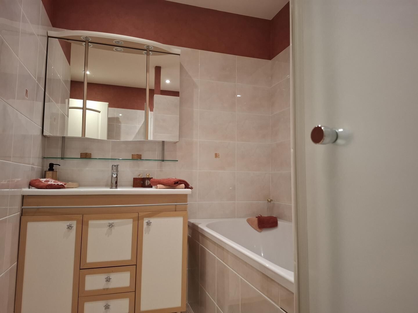 A bathroom with a vanity, mirror, and bathtub.