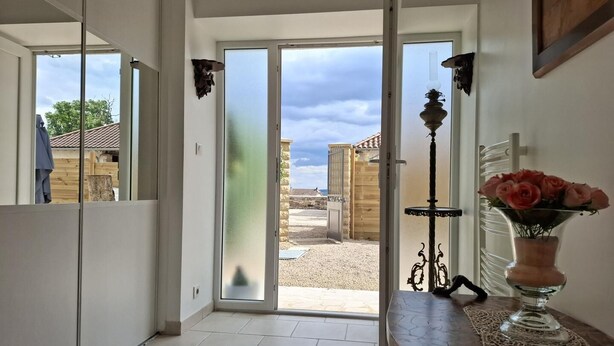 Un interior moderno con puerta de vidrio que da a un espacio exterior, una mesa con un florero y una lámpara decorativa.