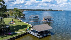 Una propiedad junto al lago con muelle, un embarcadero techado y una zona verde con juegos.