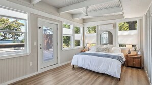 Un dormitorio con una cama grande, suelo de madera, una ventana y una puerta.