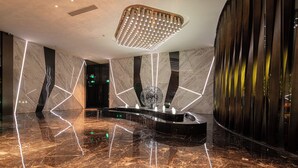 A modern lobby with a marble floor, a central water feature, and a unique lighting fixture. - K · International Hotel (Nanning)