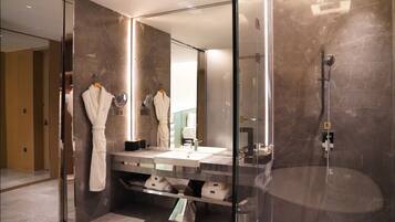 A modern bathroom with a glass-enclosed shower, a large mirror, and a vanity with a sink and towel rack.