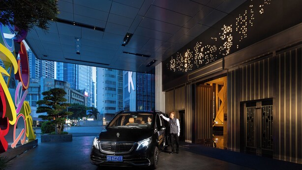 A black car parked in front of a building with a large 'K' sign, a modern interior, and a view of the cityscape. - K · International Hotel (Nanning)