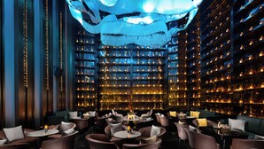 A modern bar with rows of shelves stocked with bottles, ambient lighting, and comfortable seating areas. - K · International Hotel (Nanning)