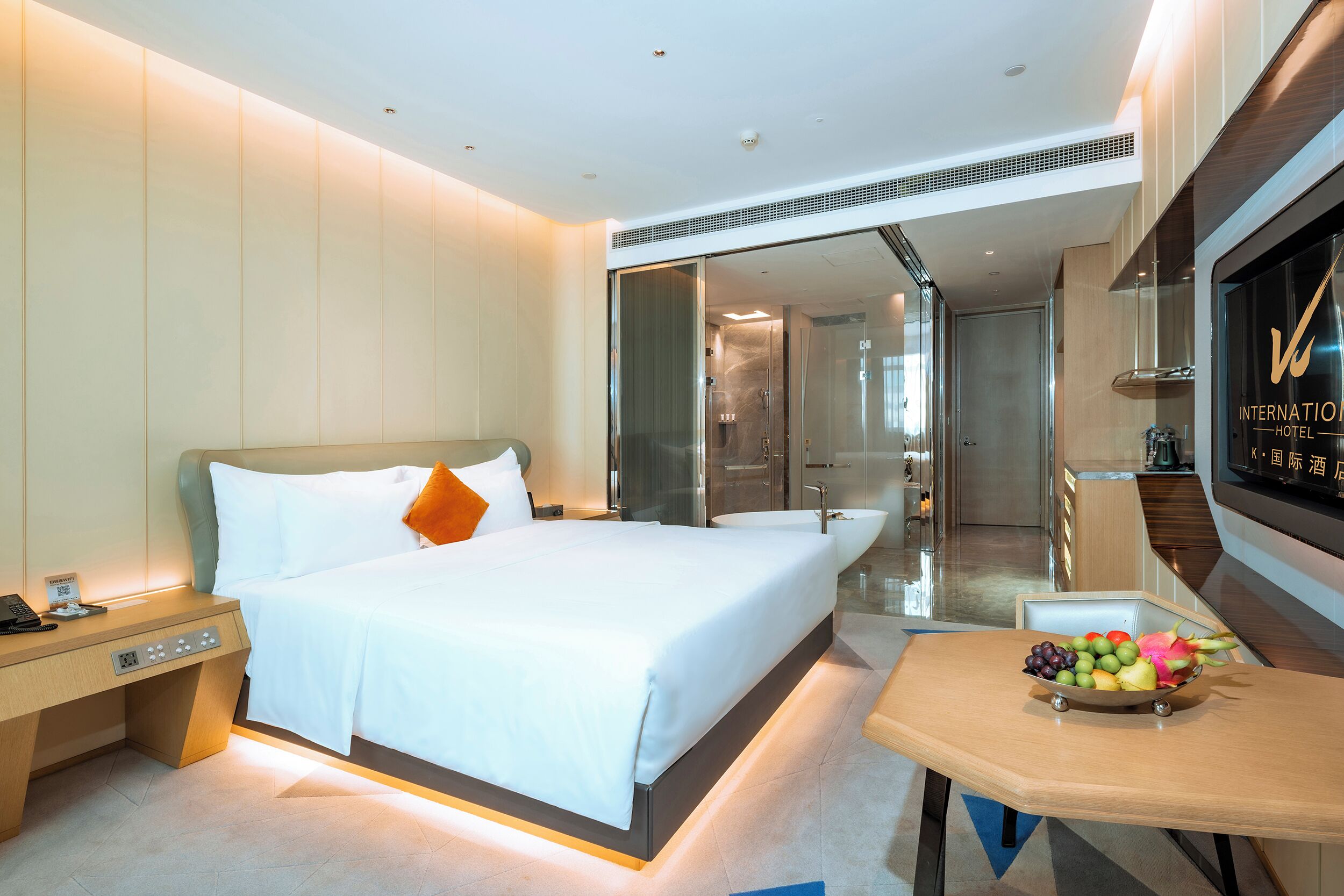 Una habitación de hotel moderna con una cama grande, una mesita de noche y un frutero sobre una pequeña mesa.