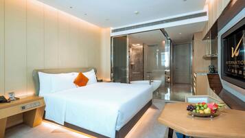 Una habitación de hotel moderna con una cama grande, una mesita de noche y un frutero sobre una pequeña mesa.