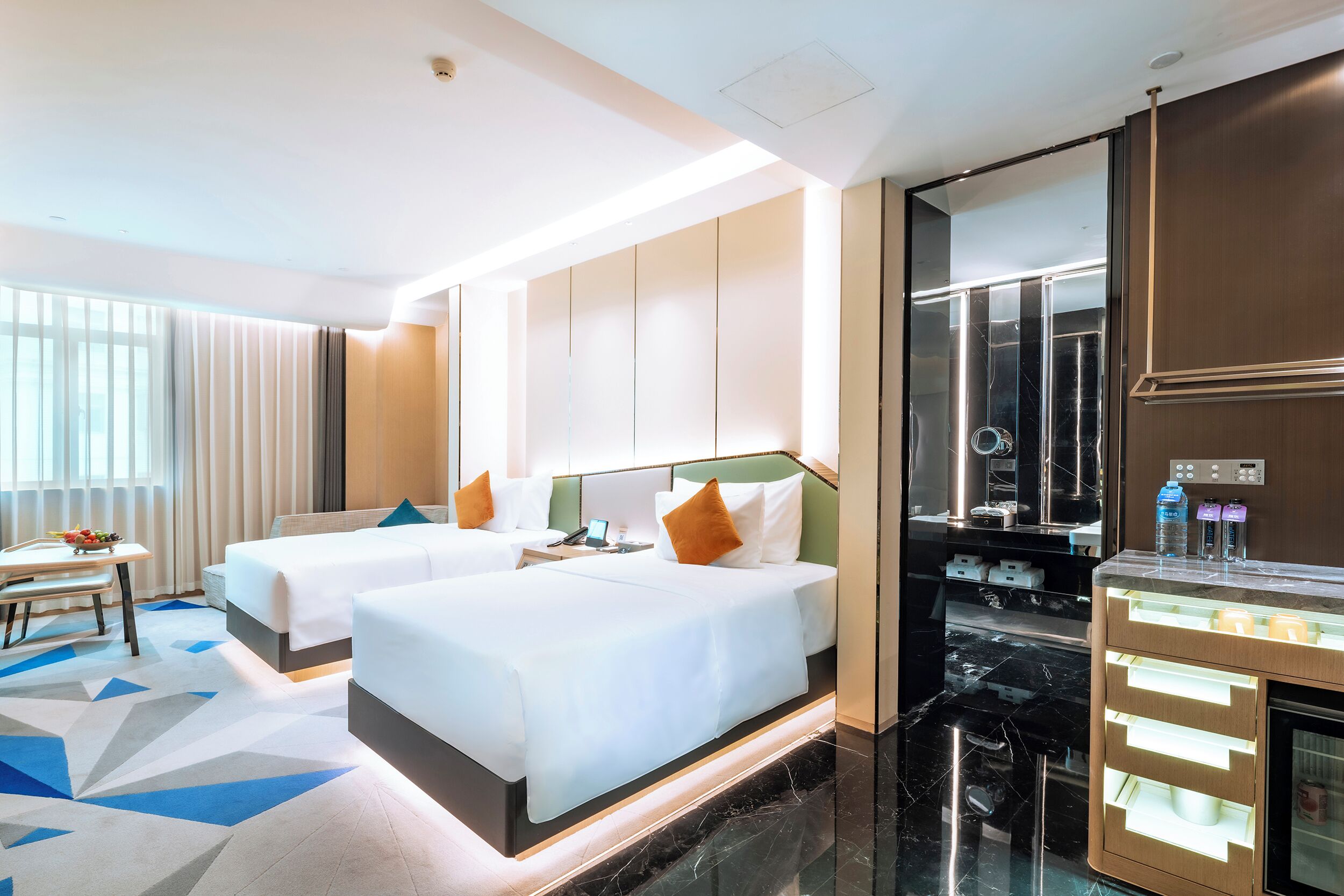 A hotel room with two beds, a desk, and a minibar.