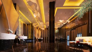 A modern lobby with a reflective floor, a reception desk, a sofa, and decorative lighting. - K · International Hotel (Nanning)
