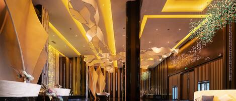 Un moderno vestíbulo con suelo reflectante, mostrador de recepción, sofá e iluminación decorativa.