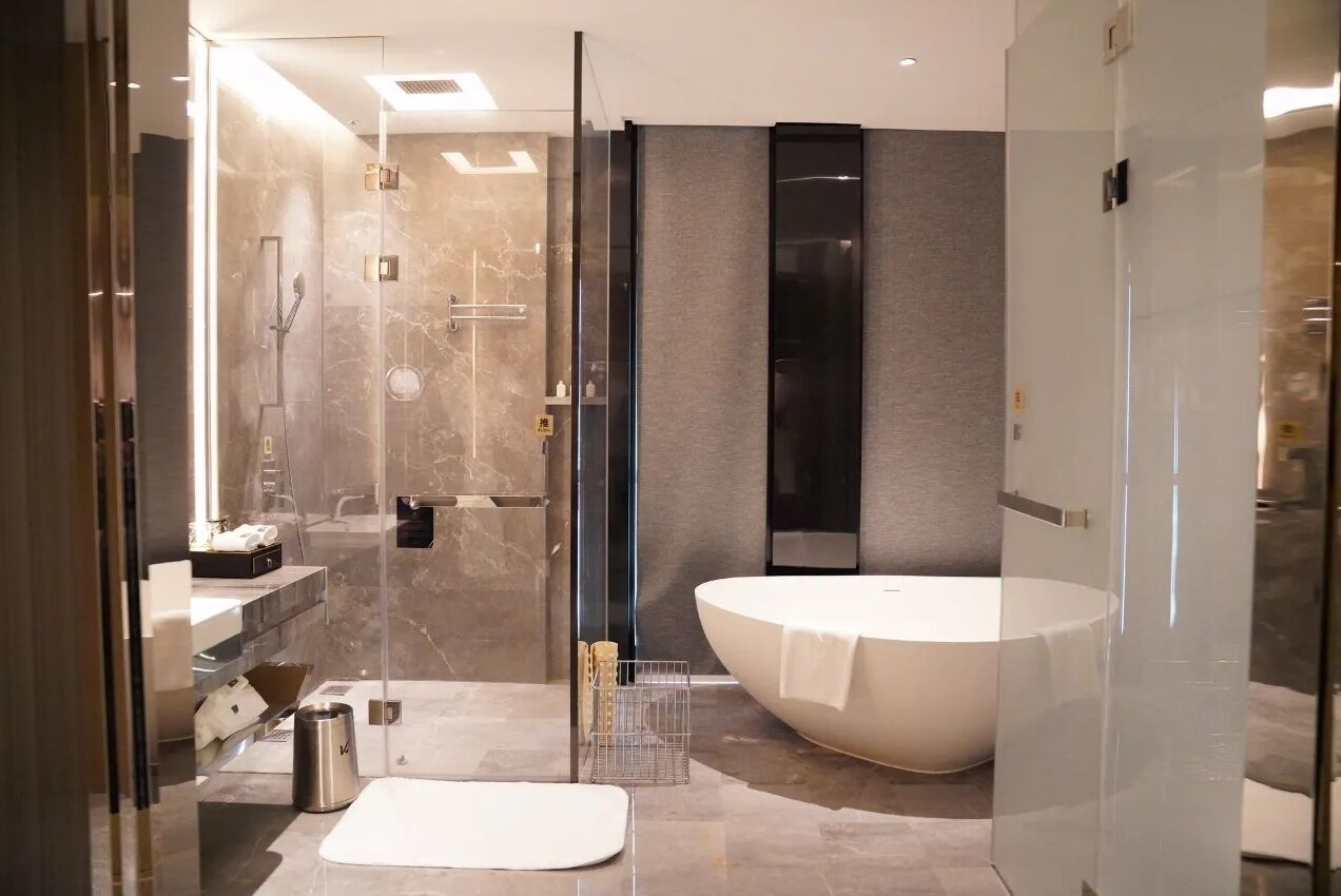 Een moderne badkamer met een douchecabine van glas, een ruime badkuip en een vloer van marmer.