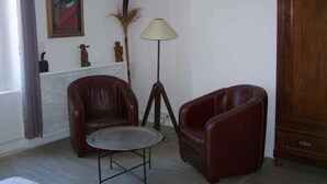 A room with two leather armchairs, a small round table, a floor lamp, and a radiator. - l'Oustal des Margaridous (LABRUGUIERE)