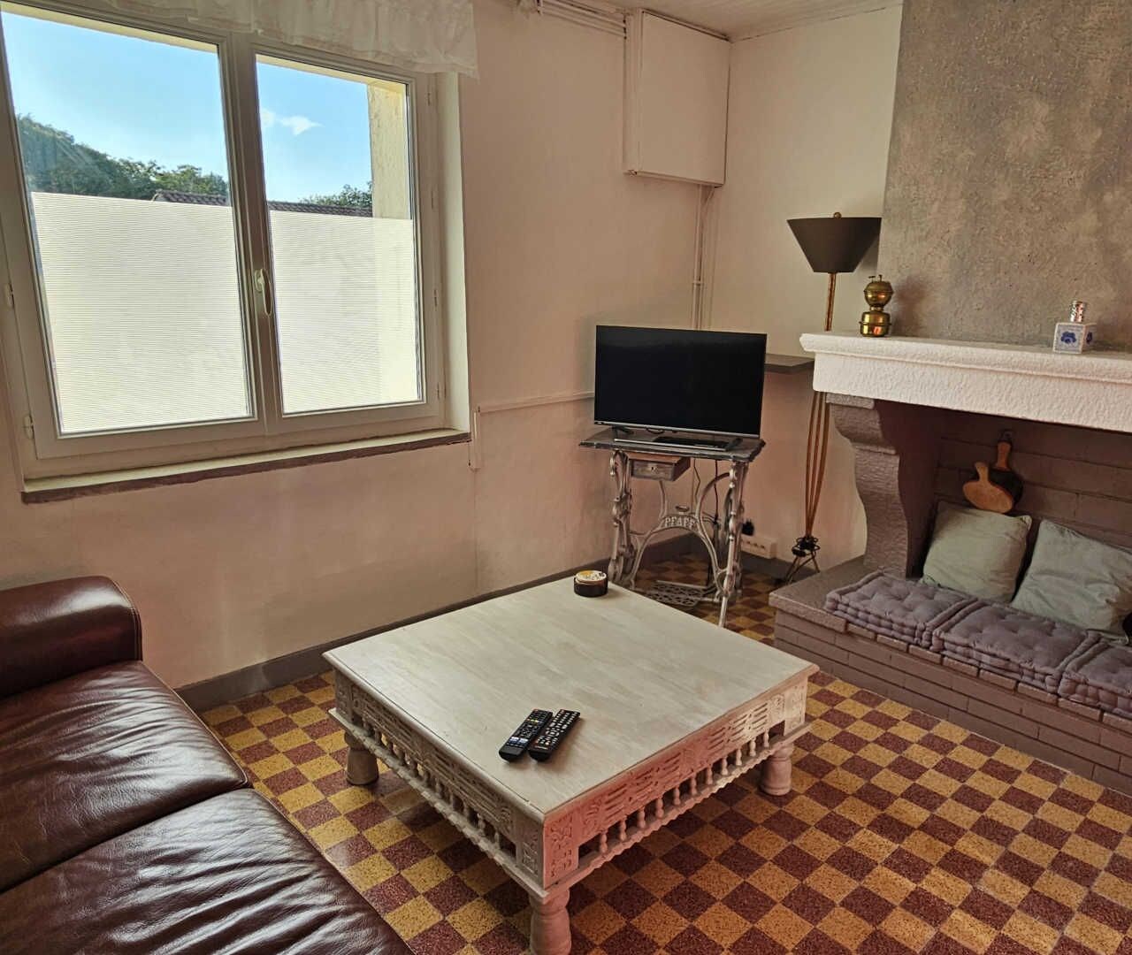 A room with a checkered floor, a television on a stand, a sofa, and a fireplace.