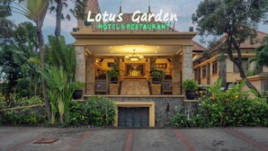 A hotel with a prominent entrance, a clock tower, and lush greenery surrounding the building.