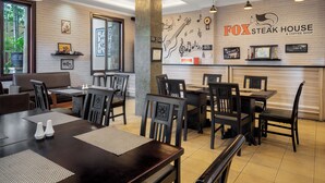 A restaurant interior with brick walls, wooden tables, and black chairs.