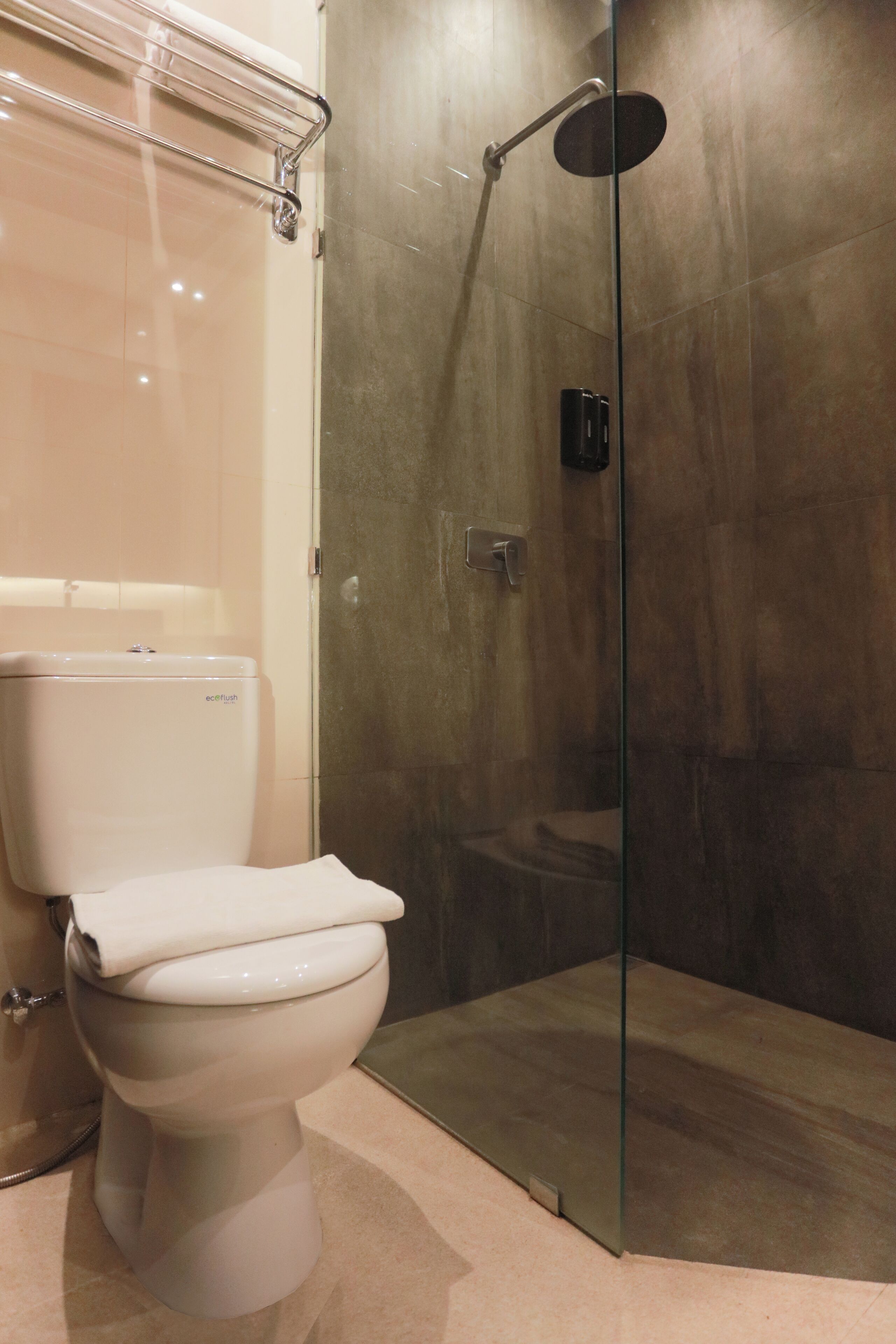 Une salle de bain moderne avec des toilettes, une douche à parois de verre et un sol carrelé de couleur beige.
