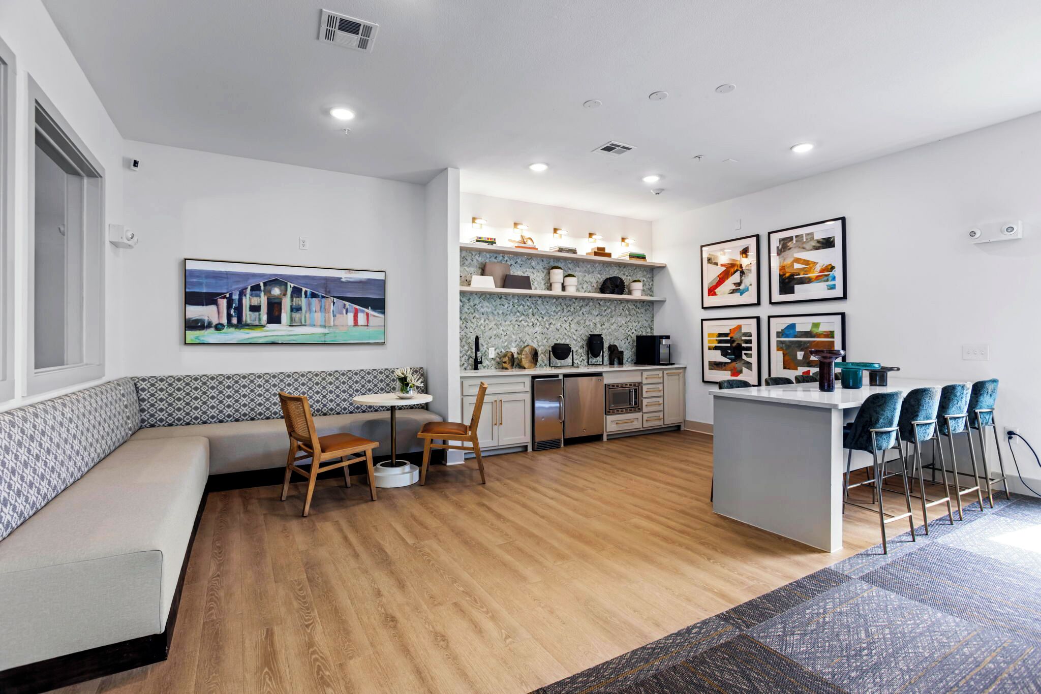 A modern kitchen with a built-in island, seating area, and artwork on the walls.