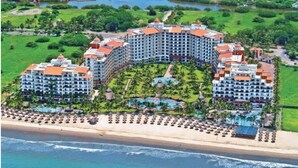 Ein großes Resort mit mehreren Gebäuden, Strandzugang und einem Poolbereich.