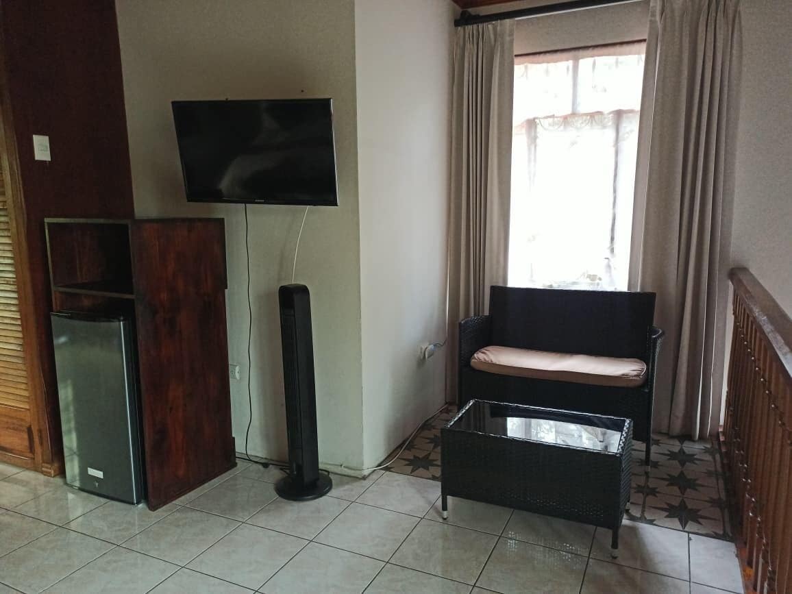 A living room with a TV, a sofa, a coffee table, and a refrigerator.