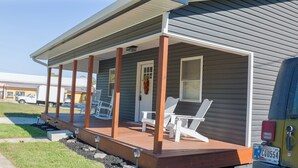 A covered porch with white chairs and a door, a truck parked nearby, and a clear sky. - In the middle of it all in French Lick!  (French Lick)