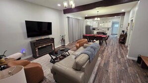 A modern living room with a flat-screen TV, a fireplace, leather sofas, and a dining area with a red tablecloth. - In the middle of it all in French Lick!  (French Lick)