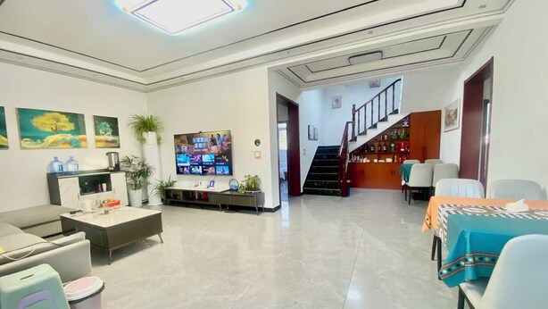 A modern living room with a flat-screen TV, a sofa, a coffee table, and a dining area with a table and chairs. - Gubeikou Great WallJuyouyuan Homestay (Miyun)