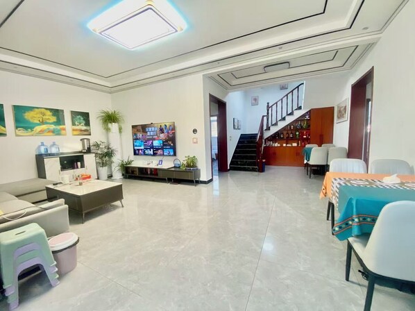 A modern living room with a flat-screen TV, a sofa, a coffee table, and a dining area with a table and chairs. - Gubeikou Great WallJuyouyuan Homestay (Miyun)