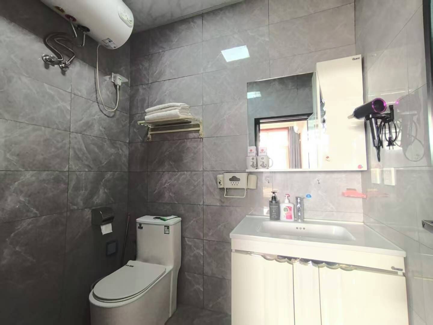 Un baño con inodoro, lavabo, espejo y ducha.