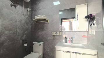 Un baño con inodoro, lavabo, espejo y ducha.