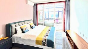 A bedroom with a bed, a nightstand, a wooden bench, and a large window with curtains. - Gubeikou Great WallJuyouyuan Homestay (Miyun)