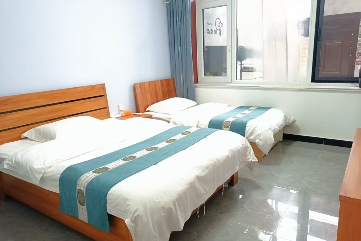 A hotel room with two beds, wooden headboards, and a window with curtains.