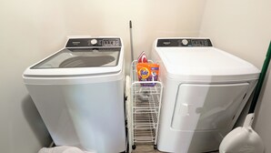 Zona de bugaderia amb dues rentadora frontals blanques i una màquina d'assecar roba blanca.