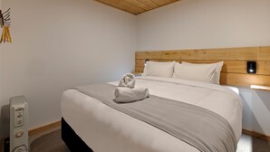A neatly made bed with a white and gray duvet, a wooden headboard, and a bedside table with a lamp. - Central Lofts 2 & 3 - Brand New! (Queenstown)