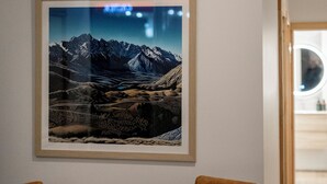 A dining area with a round table, four chairs, and a framed picture of mountains on the wall. - Central Lofts 2 & 3 - Brand New! (Queenstown)