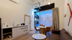 A modern kitchen with white cabinets, a dining area with a round table and four chairs, and a brown sofa. - Central Lofts 2 & 3 - Brand New! (Queenstown)