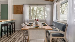 Un comedor con una mesa de madera dispuesta para cuatro personas, rodeada de sillas y un banco.