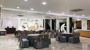 A banquet hall with round tables and chairs, a reception desk, and decorative floral arrangements. - Hotel Kingston House Lucknow (Lucknow)