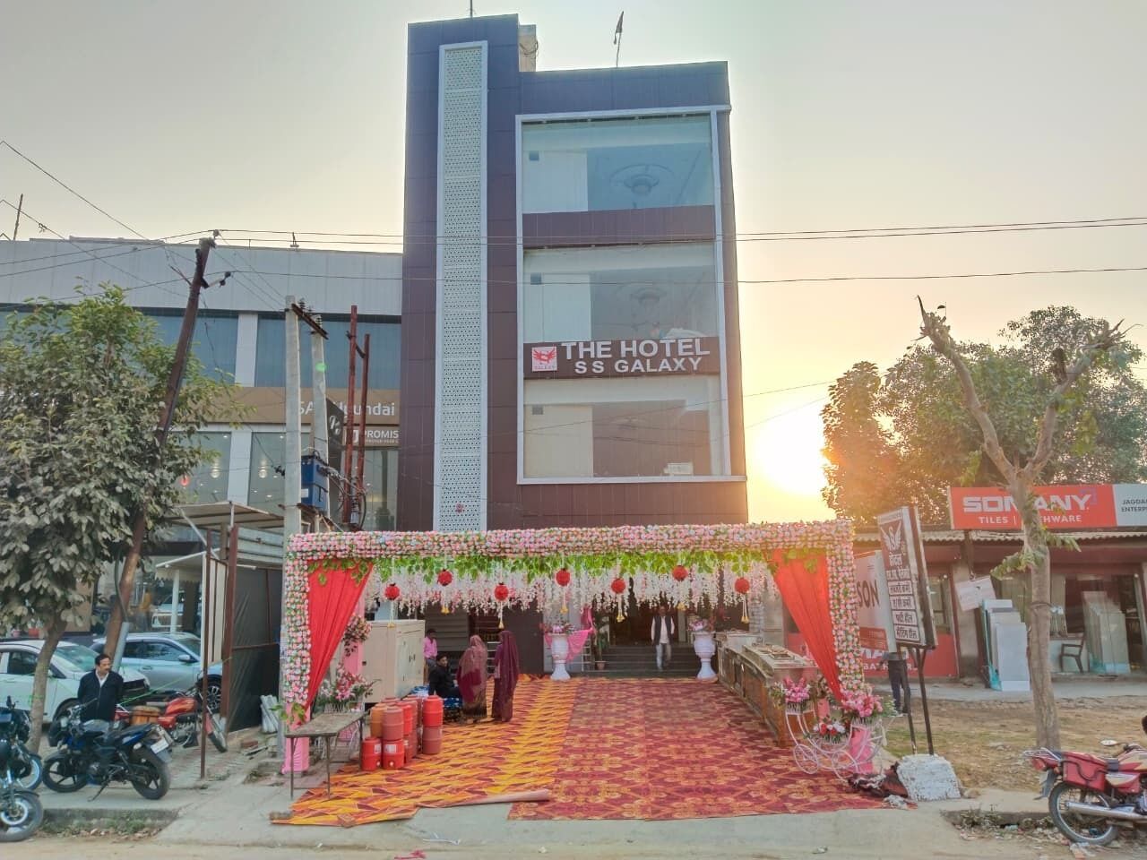 A hotel entrance with a red carpet and floral decorations.