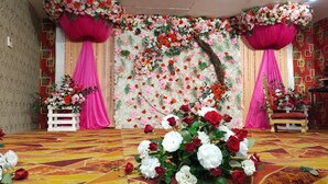 A stage with floral decorations and a patterned carpet. - Hotel The SS Galaxy (Raebareli)