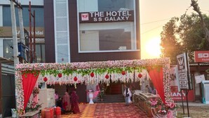 An outdoor wedding setup with a red and white floral arch, a patterned carpet, and a staircase leading to a building labeled "The Hotel SS Galaxy". - Hotel The SS Galaxy (Raebareli)