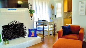 A living room with a fireplace, a dining area with a table and chairs, and a kitchen area with cabinets. - The Elisha House - Cozy Stay Near Local Eats (Katy)