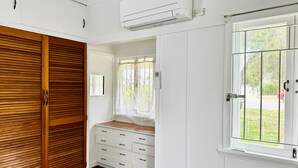 A room with a wooden wardrobe, a white dresser, and a window with a view of greenery. - Affordable Chermside Home near Hospital & Westfield (Chermside)